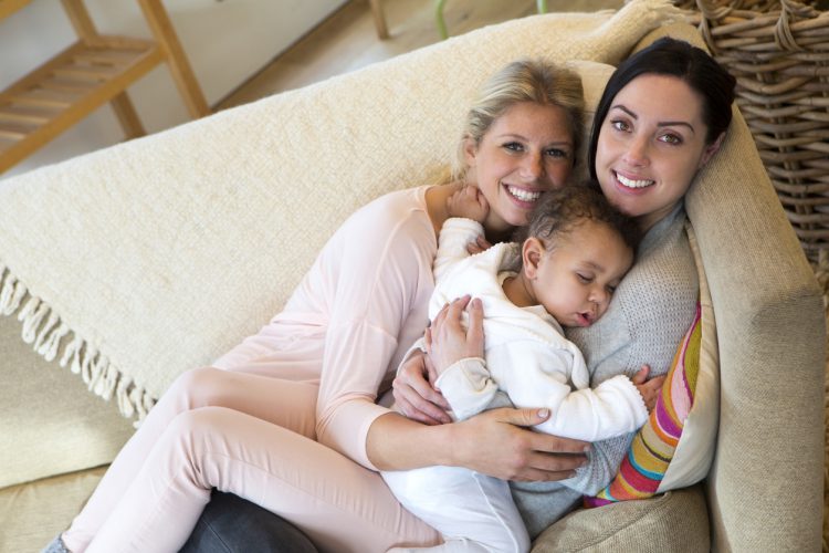 Two Women Holding Baby on Couch