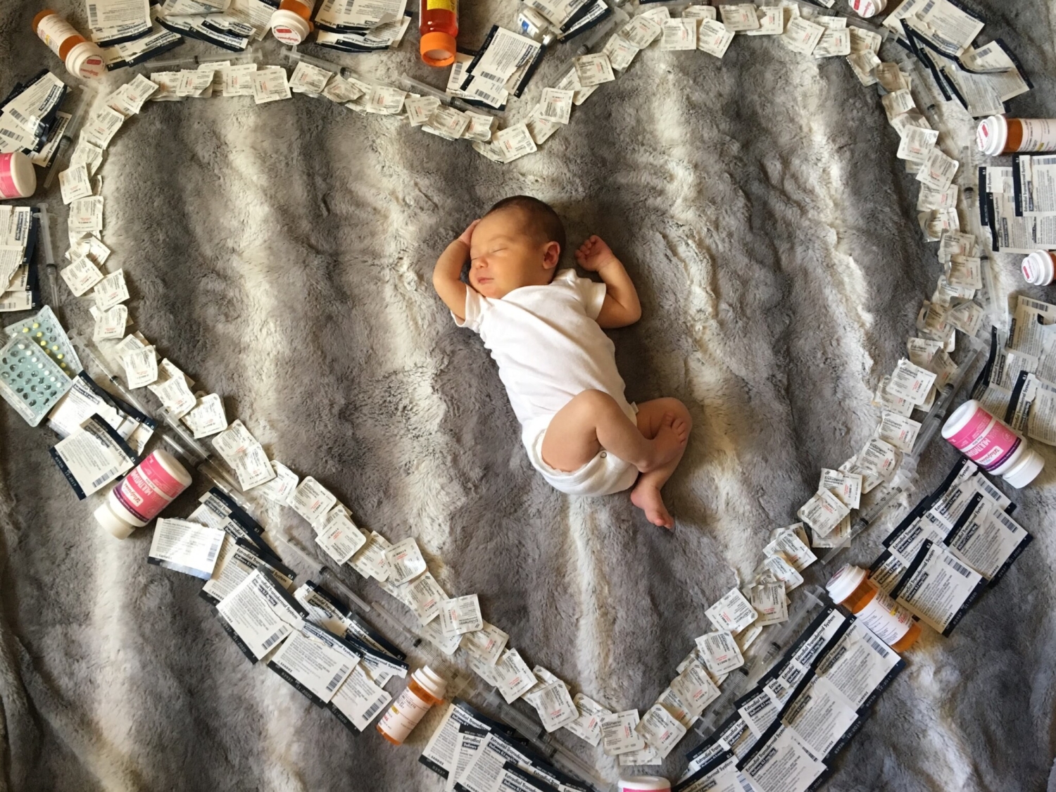 Baby lying on floor surrounded by IVF medical supplies