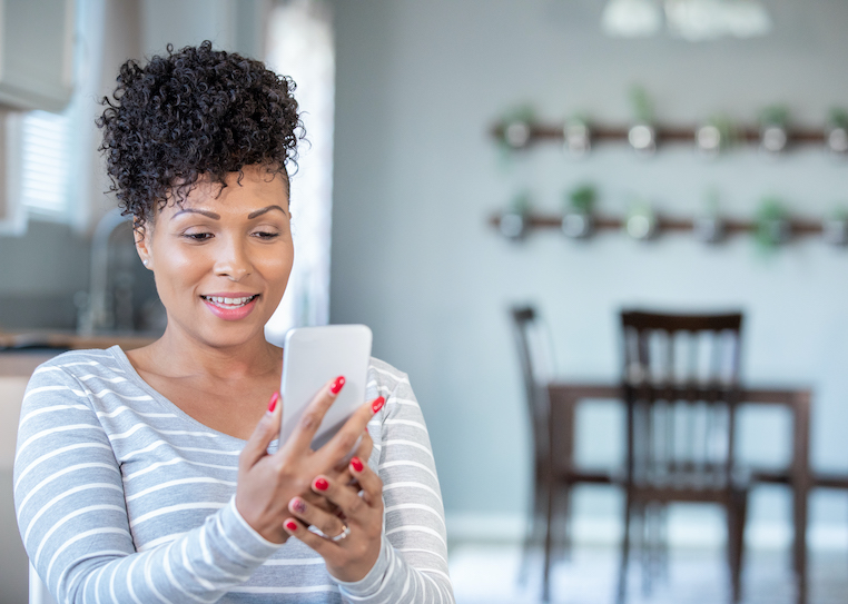 Black woman uses smart phone for virtual doctor's appointment from home