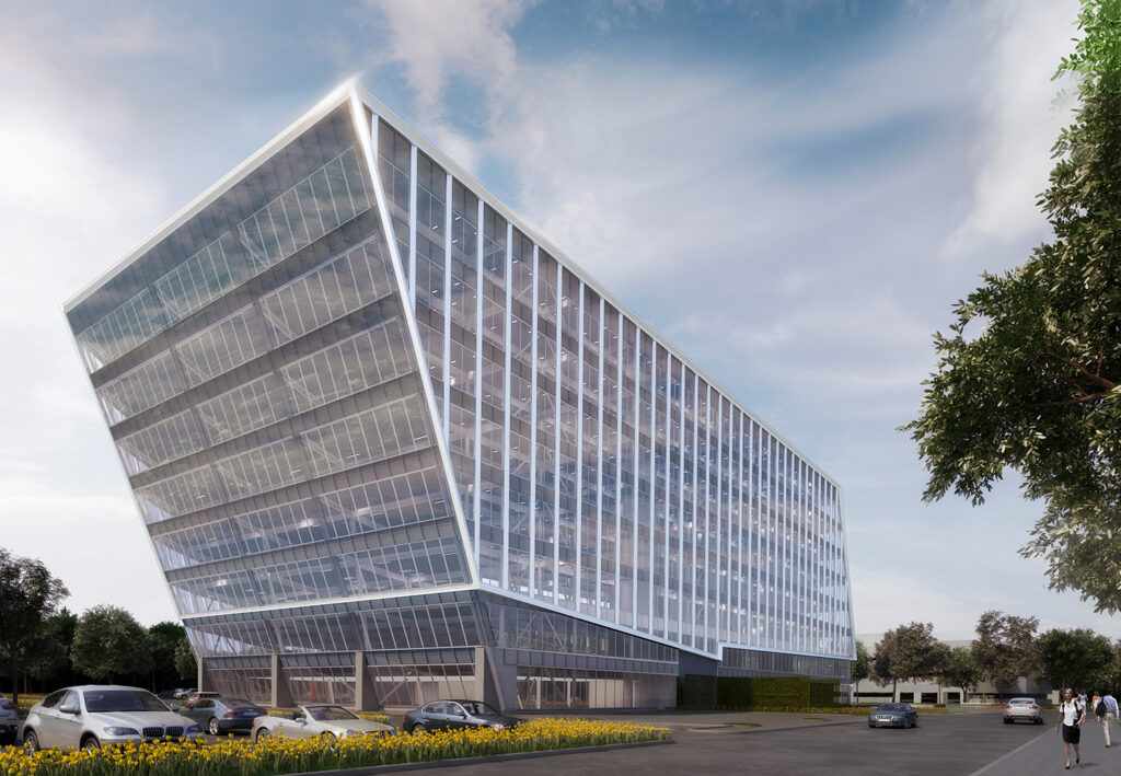 A modern, glass-fronted office building with a dramatic slanted design rises above a landscaped area with parked cars and a few people walking, set against a partly cloudy sky.