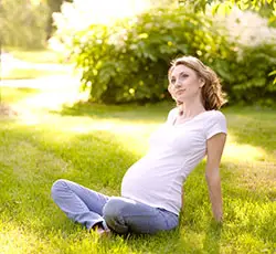 potentially underweight pregnant woman sitting in a park