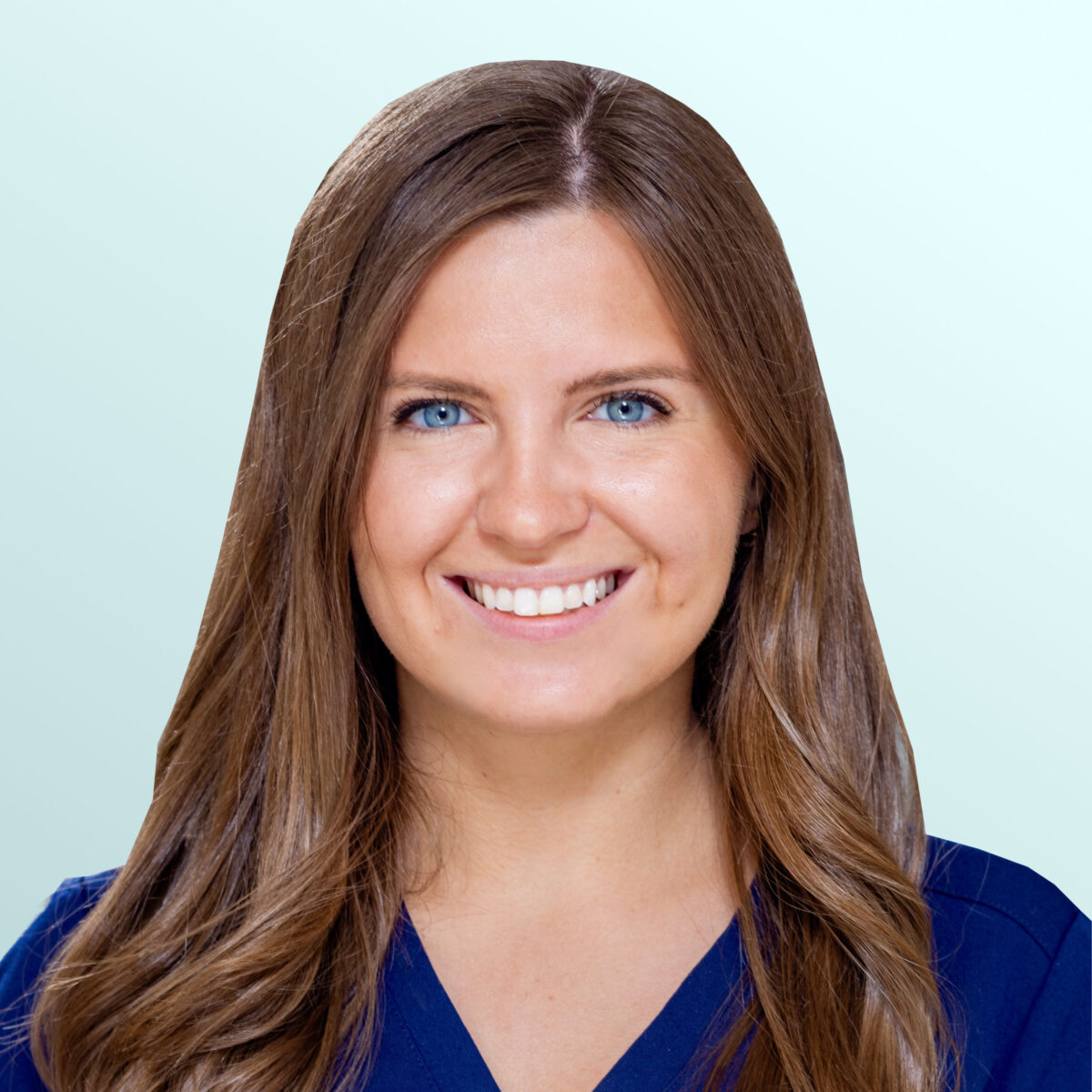 A woman with long brown hair and blue eyes, wearing a navy blue top, smiling at the camera against a light blue background.