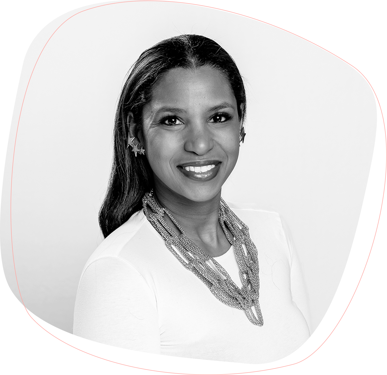 Black and white portrait of a woman with long dark hair, wearing a white top, a multi-strand beaded necklace, and star-shaped earrings, smiling at the camera against a plain background.