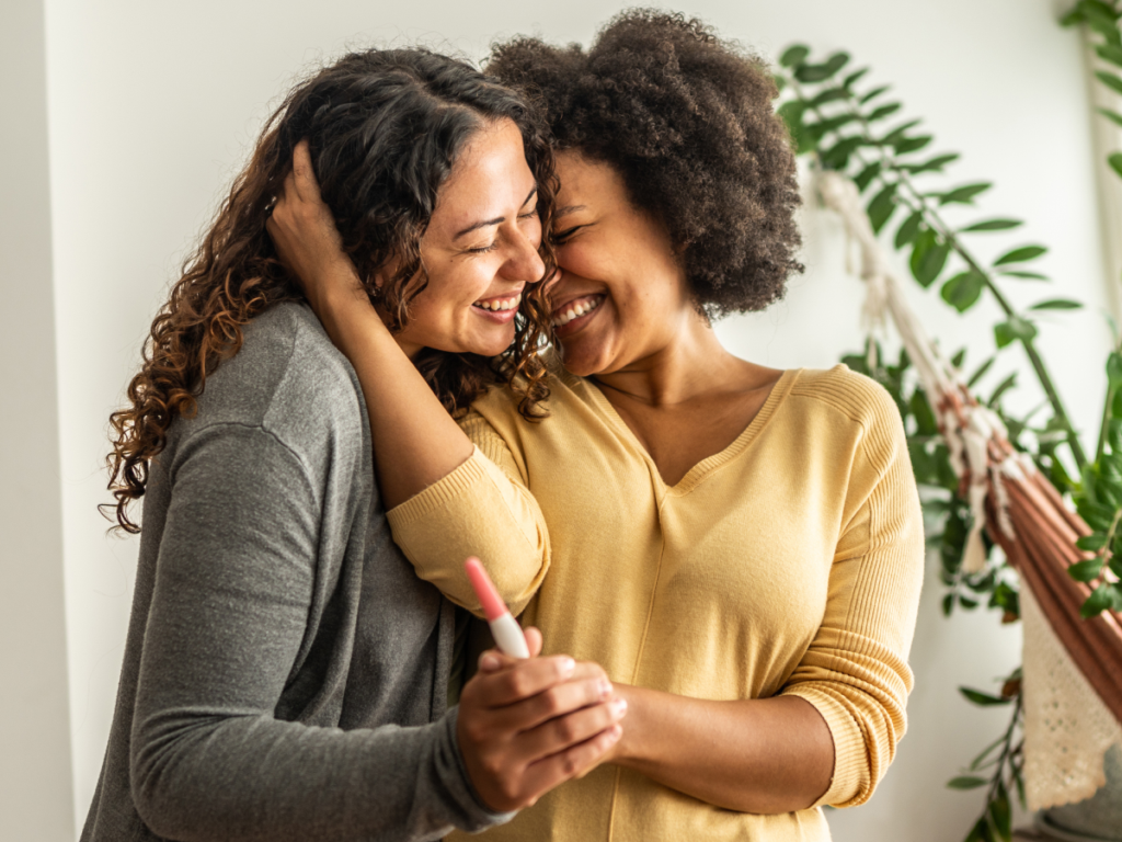 photo of a lesbian mixed race couple holding a positive pregnancy test