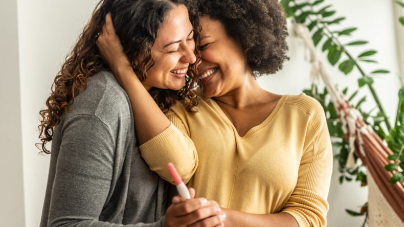 photo of a lesbian mixed race couple holding a positive pregnancy test