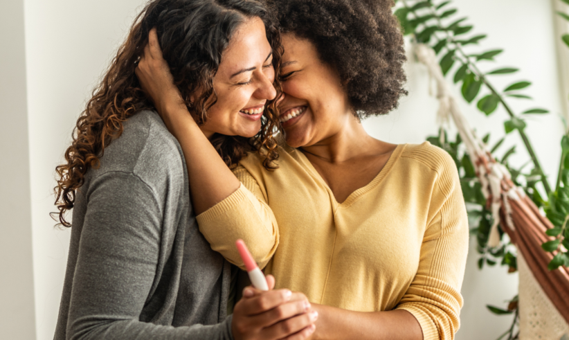 photo of a lesbian mixed race couple holding a positive pregnancy test