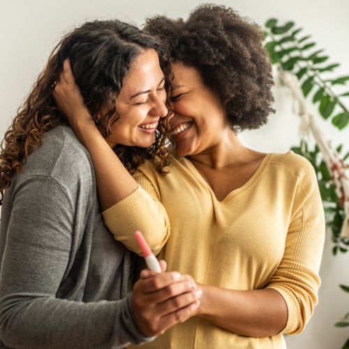photo of a lesbian mixed race couple holding a positive pregnancy test