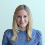 A woman with straight blonde hair and blue eyes is smiling at the camera. She is wearing a soft blue sweater and is posed against a light blue background.