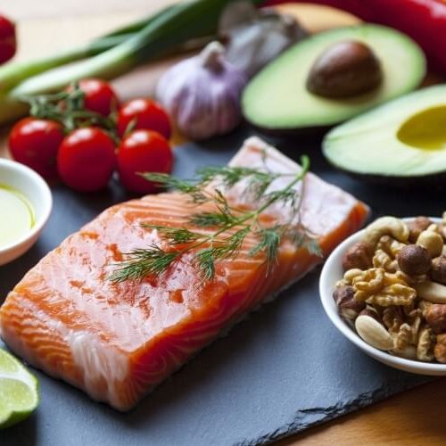 A slab of raw salmon with a sprig of dill sits on a slate board, surrounded by cherry tomatoes, green onions, garlic, red chili, half an avocado, mixed nuts, a lime wedge, and a small bowl of olive oil.