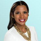 A woman with long dark hair wearing a white top, gold star-shaped earrings, and layered gold necklaces smiles against a light blue background.